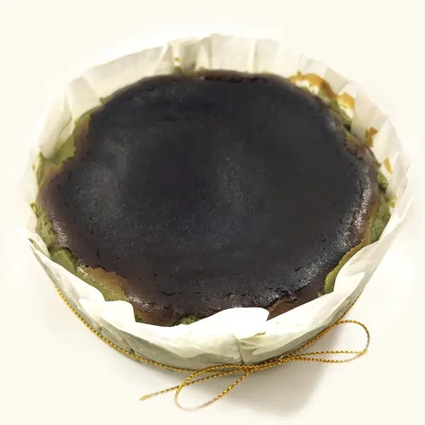 Whole Matcha Burnt Cheesecake in fluted parchment with gold string