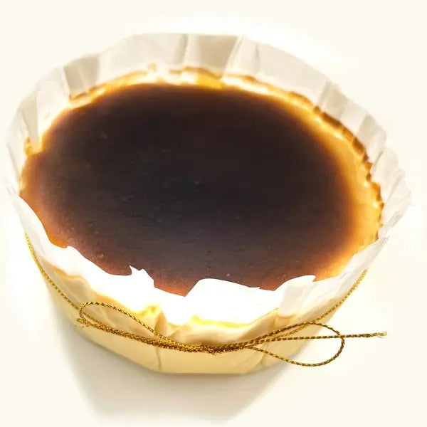 Whole Rum and Raisin Burnt Cheesecake in fluted parchment with gold string