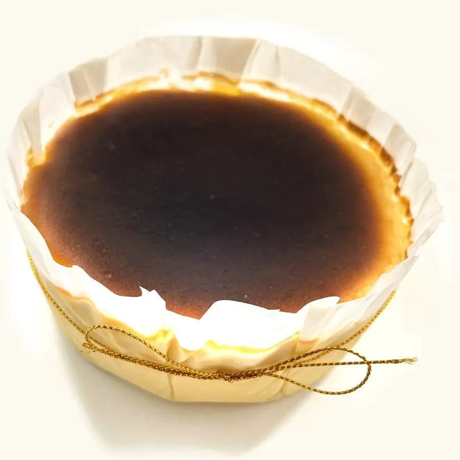 Whole Rum and Raisin Burnt Cheesecake in fluted parchment with gold string