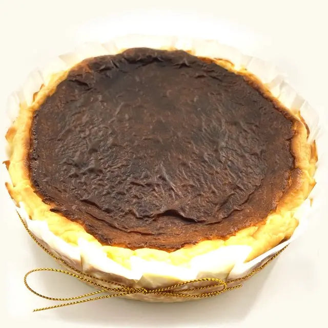 Whole Sugar-Free Keto Burnt Cheesecake with a crinkled dark top and gold string