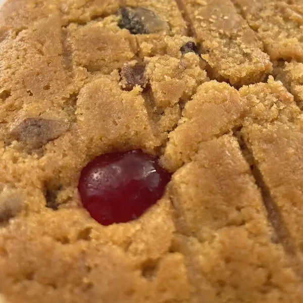 Close-up of the Alcoholic Fruit Cake top: a glacé cherry and fruit in the golden crumb