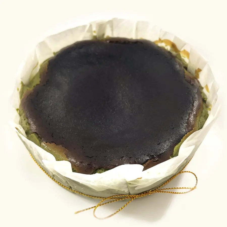 Whole Matcha Burnt Cheesecake in fluted parchment with gold string