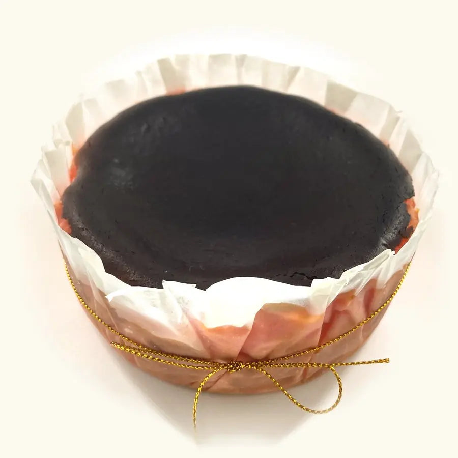 Whole Strawberry Burnt Cheesecake in fluted parchment with gold string, pink sides