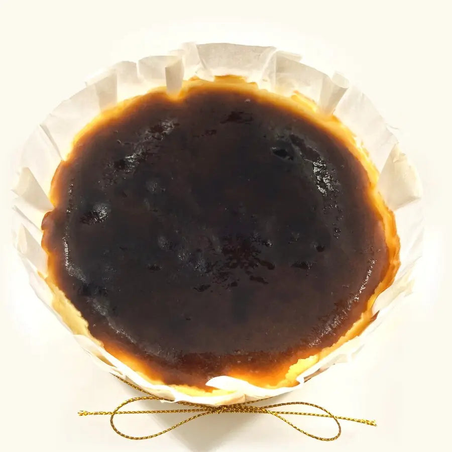 Whole Original Basque Burnt Cheesecake in fluted parchment with gold string