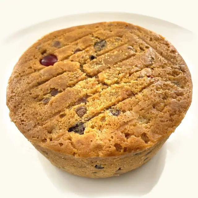 Whole Alcoholic Fruit Cake, golden and scored on top, with a glacé cherry