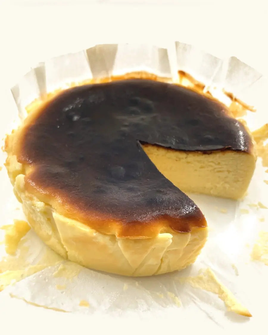 The whole Burnt Cheesecake on its baking paper, a slice taken out