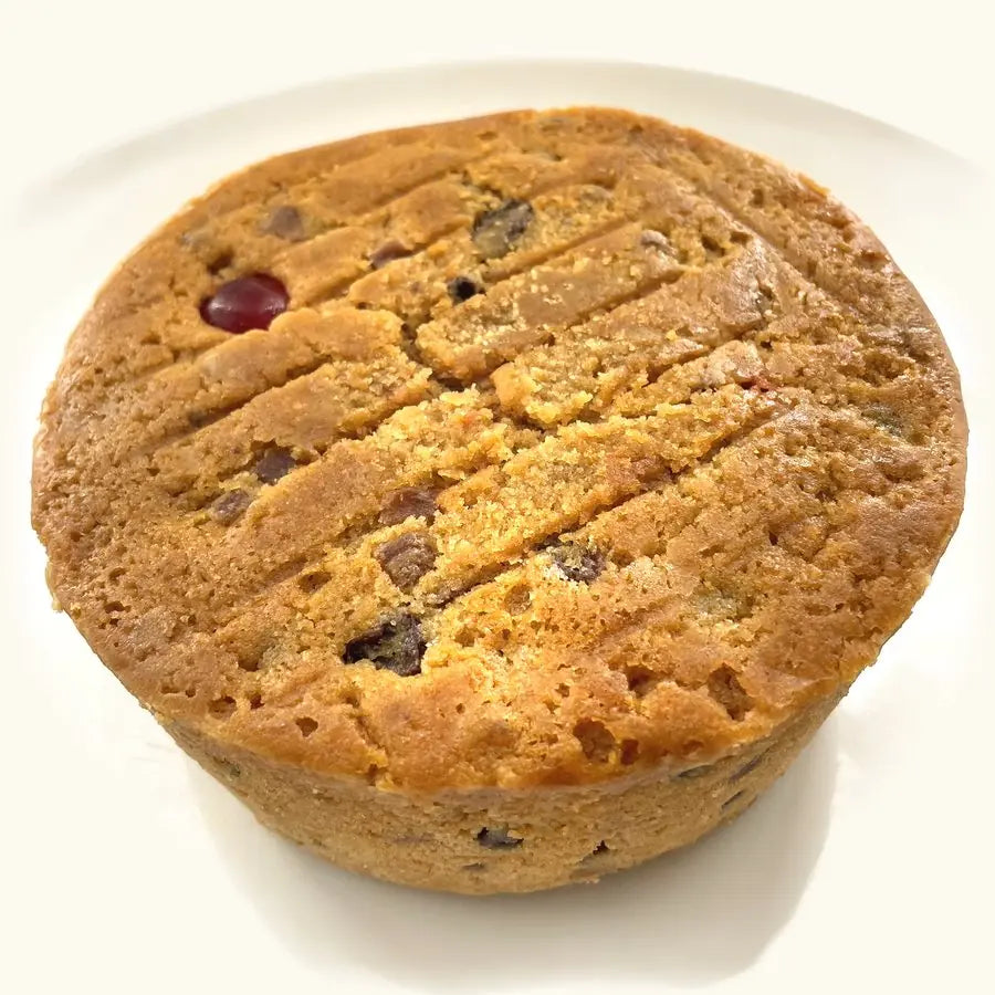 Whole Alcoholic Fruit Cake, golden and scored on top, with a glacé cherry