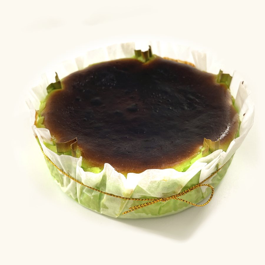 Whole Pandan Burnt Cheesecake in fluted parchment with gold string, green sides