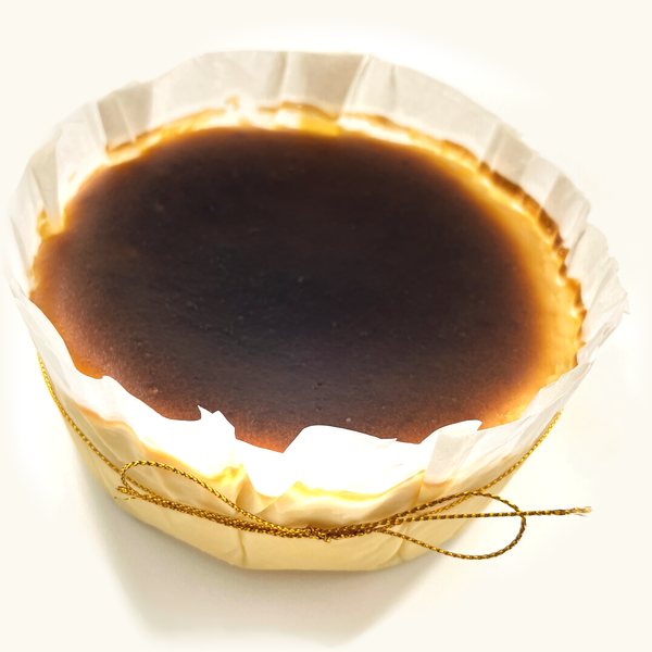 Whole Rum and Raisin Burnt Cheesecake in fluted parchment with gold string