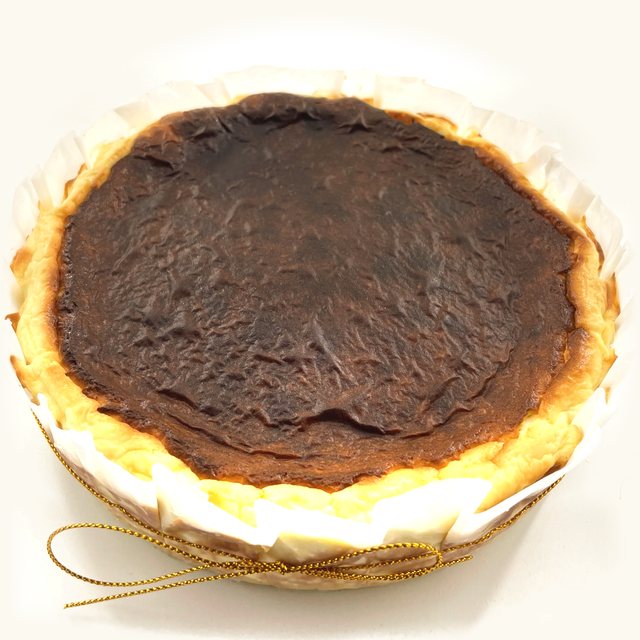 Whole Sugar-Free Keto Burnt Cheesecake with a crinkled dark top and gold string